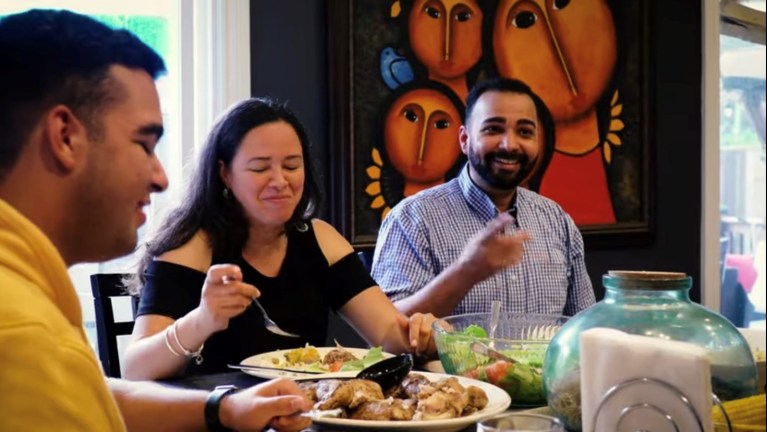 People smiling and eating food at a dinner table