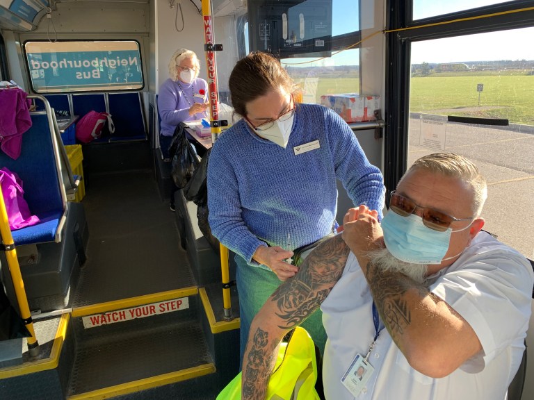 Region staff provide a vaccine inside a bus being used as a mobile vaccine clinic.