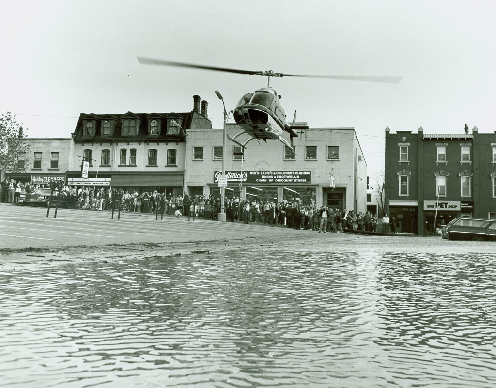 A helicopter hovers low above a flooded street.