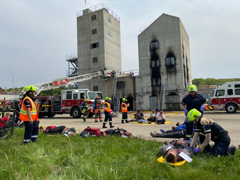 Paramedics at a large training scenario work on volunteers who pretend to be injured in an accident.