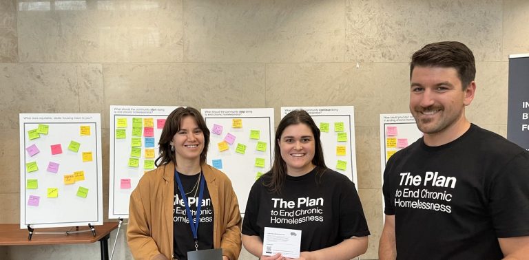 Three Region of Waterloo staff members at a public event to gather feedback for the new Plan to End Chronic Homelessness.