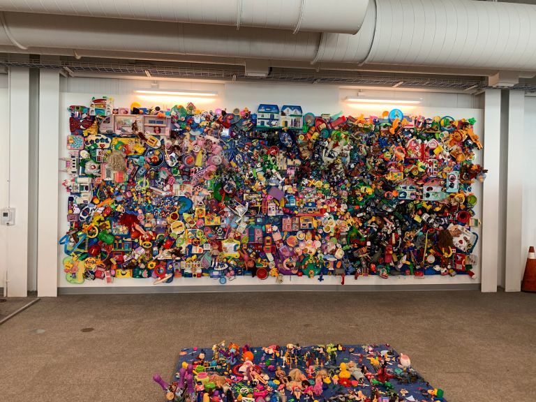 A colourful art display on a wall at the Waterloo Region Airport, made up of old toys and other recycled items.
