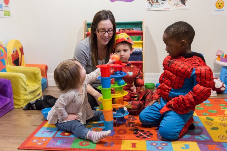 An Early Childhood Educator works with several children in a colourful environment.