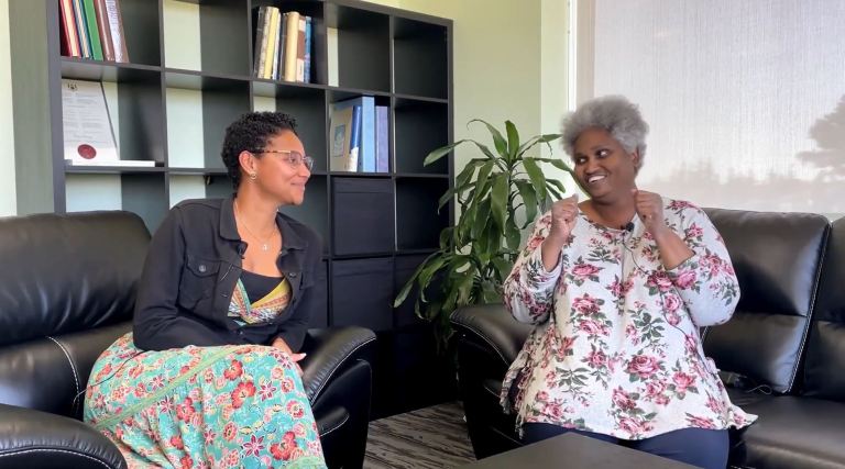 Two women seated on a couch for an interview.