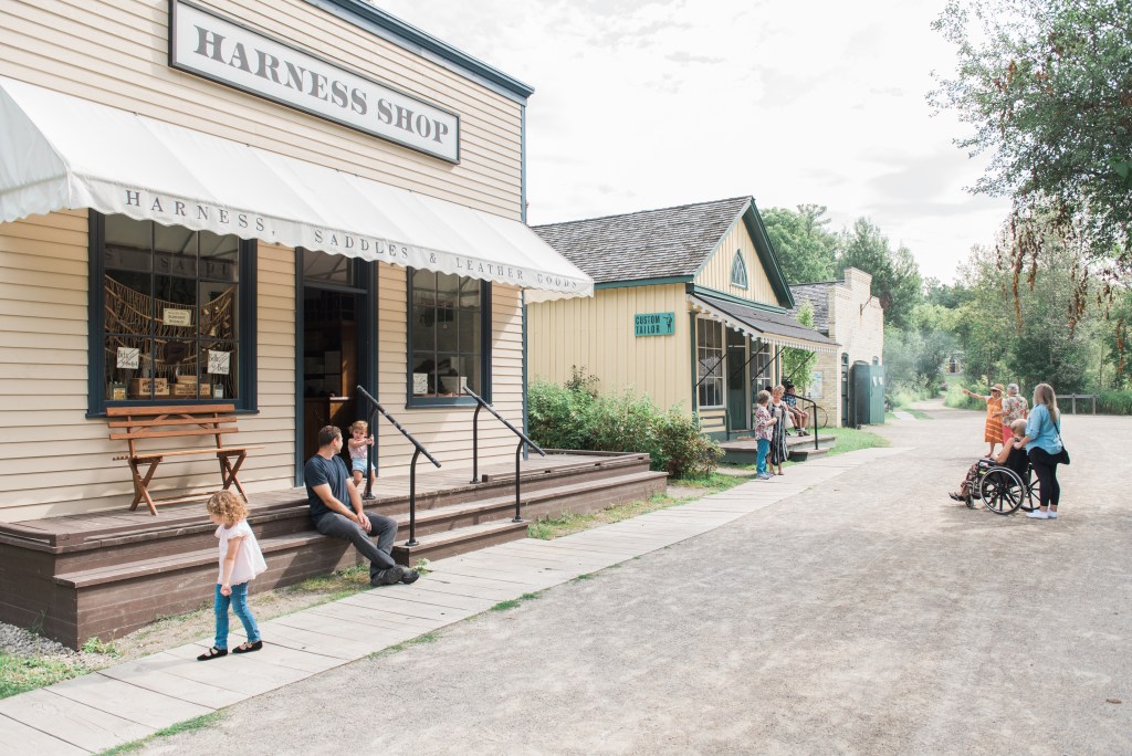 Visitors and staff in historical costumer walk outside the old buildings at Doon Heritage Village.