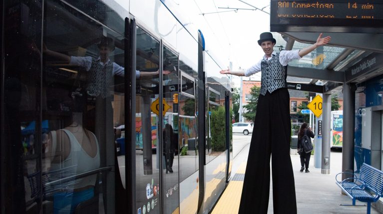 A performer on stilts stands outside an ION train for the LRT's 5th anniversary.