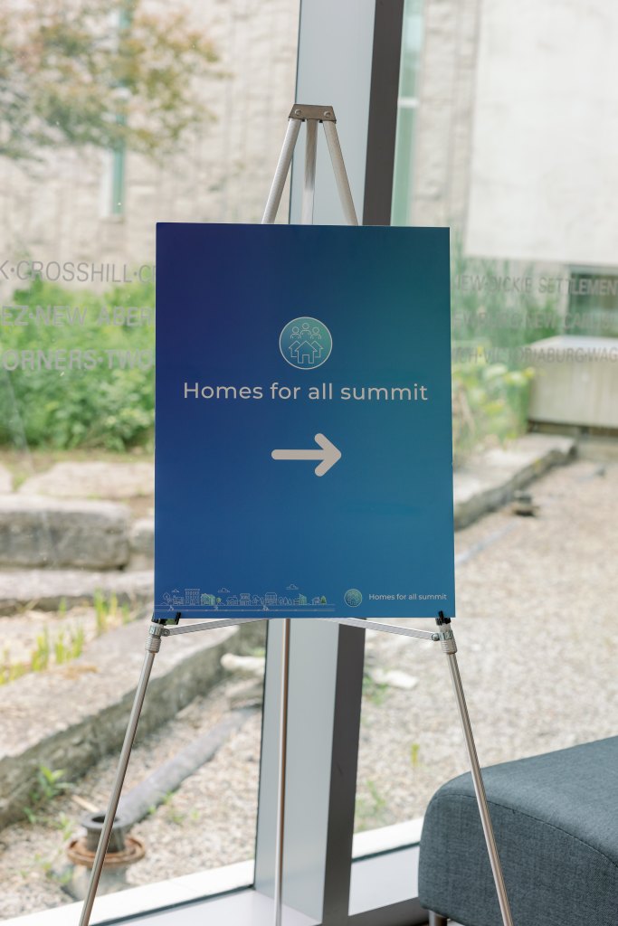A blue sign for the Homes for All Summit.