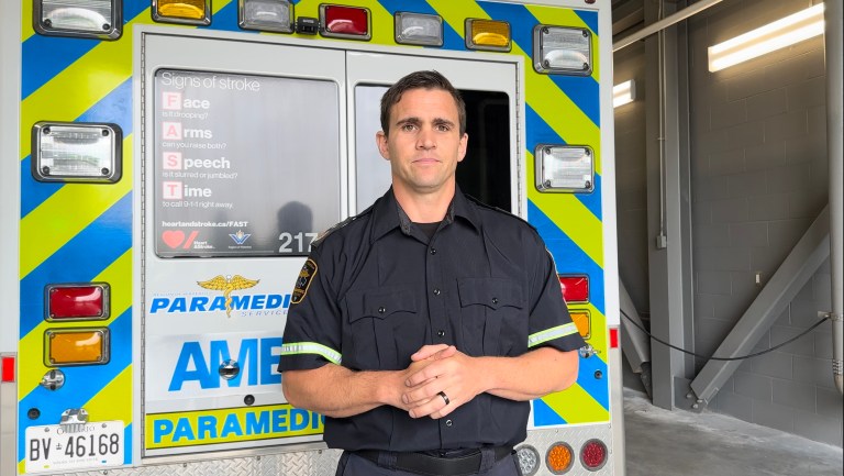 A paramedic stands in front of an ambulance.