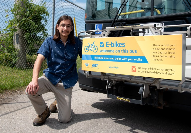 A young man poses in front of a Grand River Transit bus.