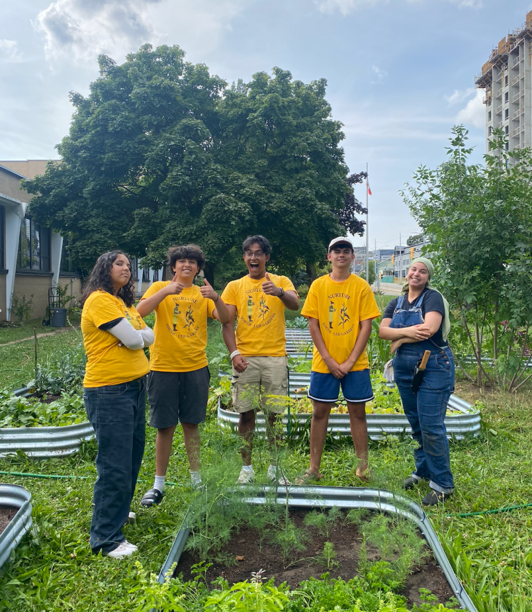Five students in matching yellow t-shirts show off their gardens