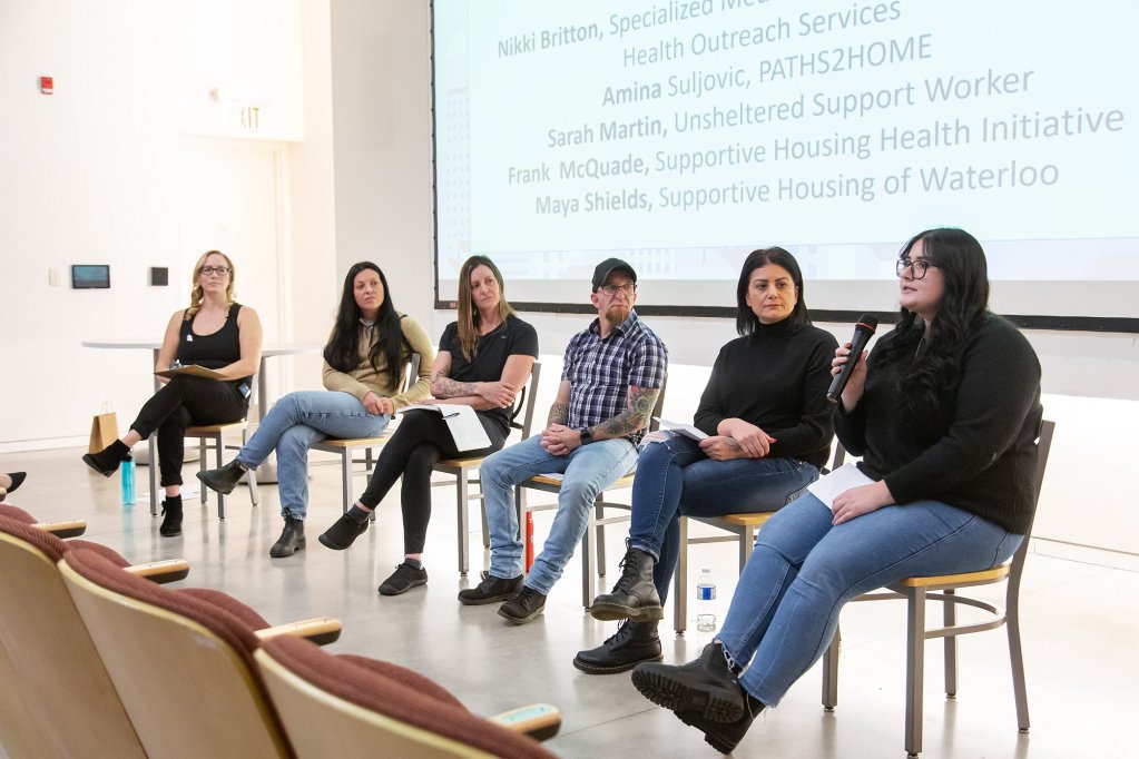 A panel of six people sit on stage to discuss housing issues.