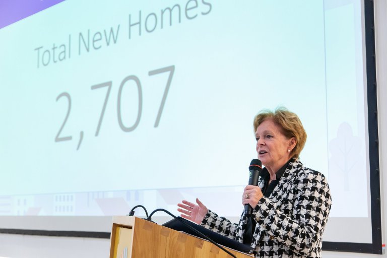 Regional Chair Karen Redman stands at a podium to announce reaching the Building Better Futures goal.