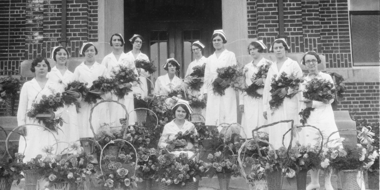 A group of nurses pose in a black and white photo.