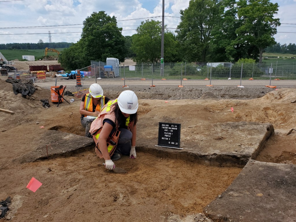 Group of people wearing vests and hard hats work outside.