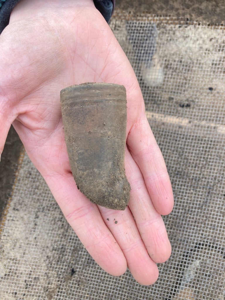 An uncovered artifact sits in someone's hand.