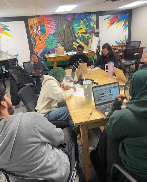 Teens sit around a table, working on a project.