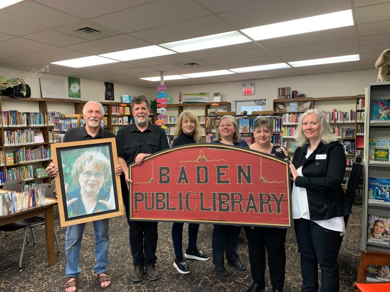 Donors of the antique "Baden Public Library" sign present it to Region of Waterloo library staff inside the Baden branch.
