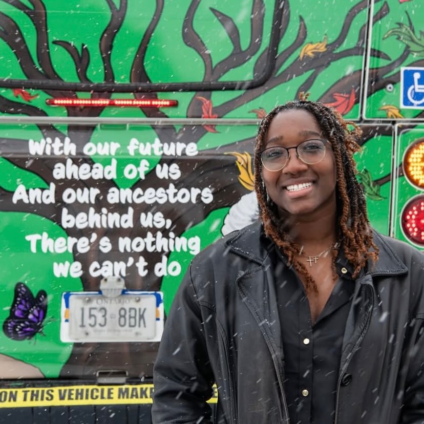 A young woman smiles in front of an illustrated bus.