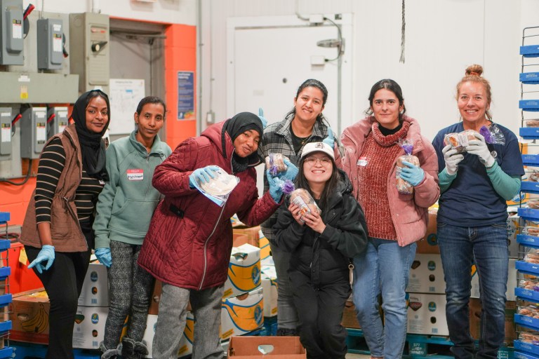 Seven workers pose in The Food Bank of Waterloo Region's distribution warehouse.