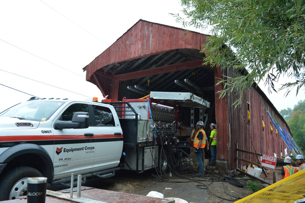 Construction crews work near a pick-up truck at the entrance  to the West Montrose Bridge.