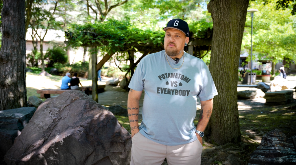 Indigenous artist Kevin George speaks outside in a park area.